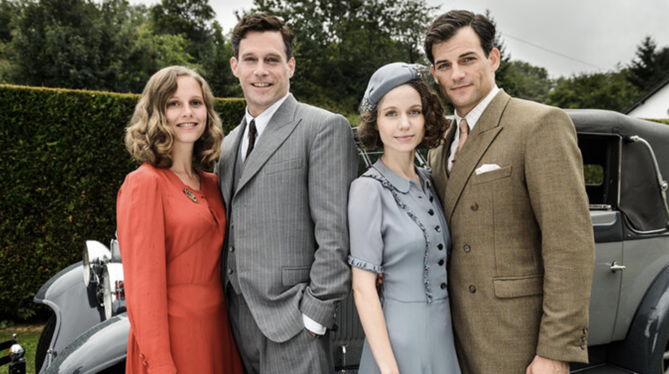The Brothers standing with their wifes in front of a vintage car